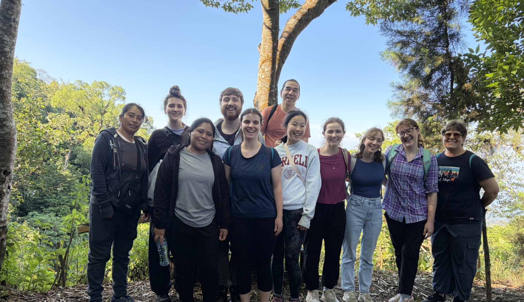 A group of FARVets volunteers gathered outdoors among trees on a sunny day